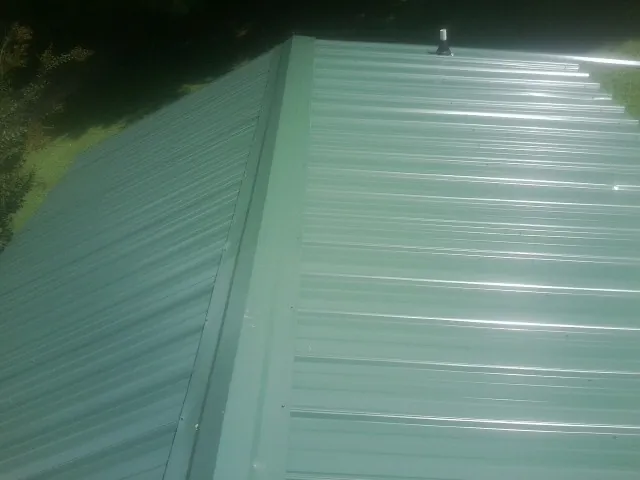 New green metal panels meeting at the ridge of a roof — Flat Roof Repair work by our crew in Stahlstown