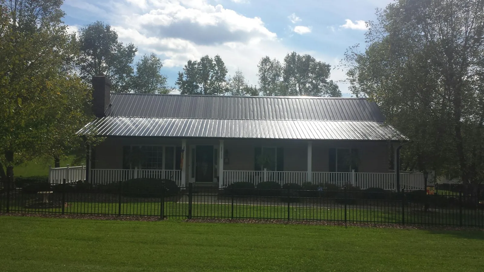 Gray metal roof on a brick ranch with a full width front porch — Gutter Guard Installation work by our crew in Stahlstown