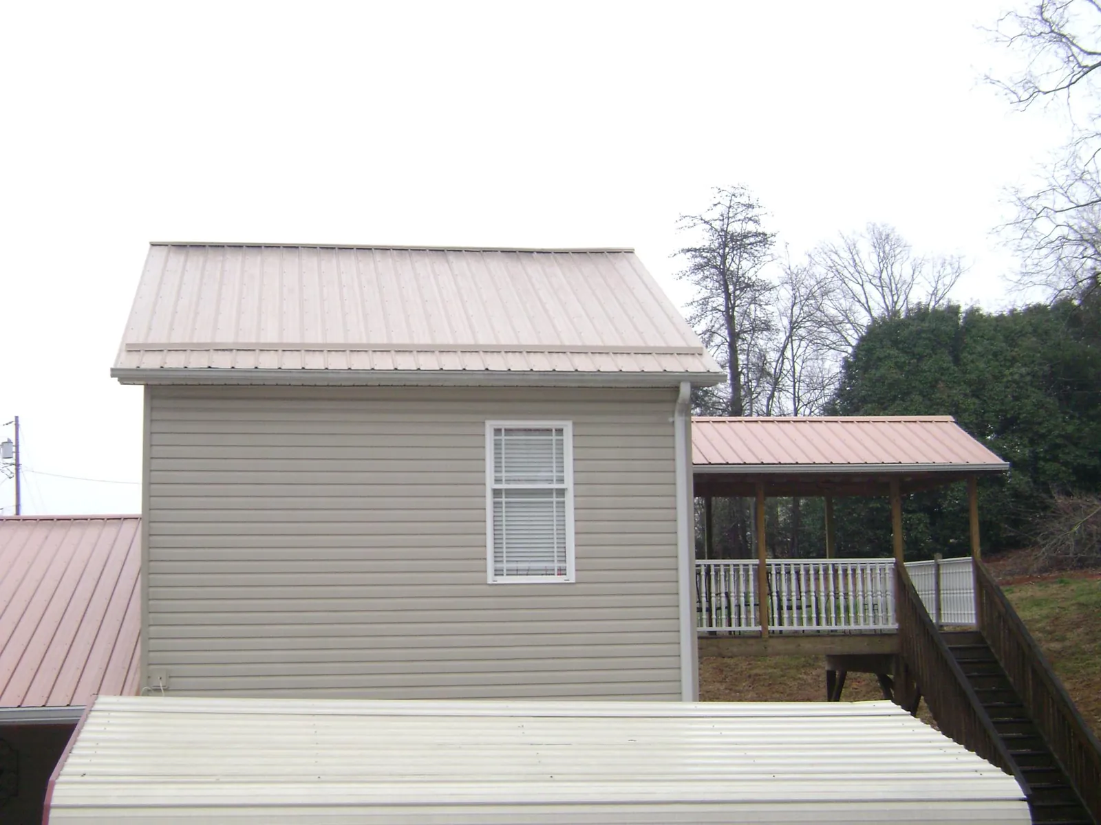 Tan metal roofs on a two story addition and attached porch, from a Roof Replacement job in Stahlstown