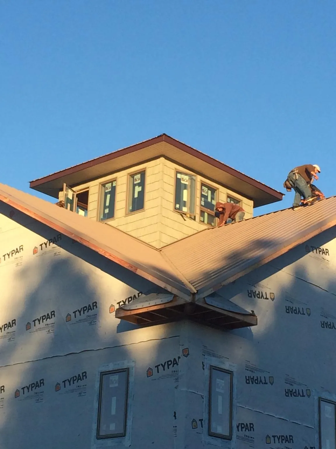 Roofers working around a rooftop cupola on a new metal roof at sunset — Roof Waterproofing in Stahlstown by Roofing Brothers